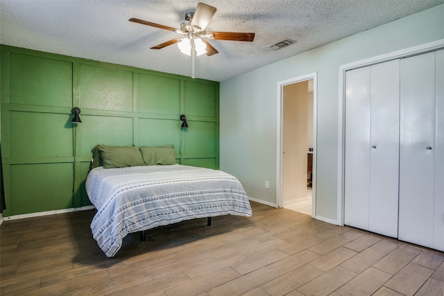 bedroom featuring a textured ceiling, light wood-type flooring, and ceiling fan