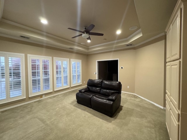 carpeted cinema with ceiling fan, a tray ceiling, and ornamental molding