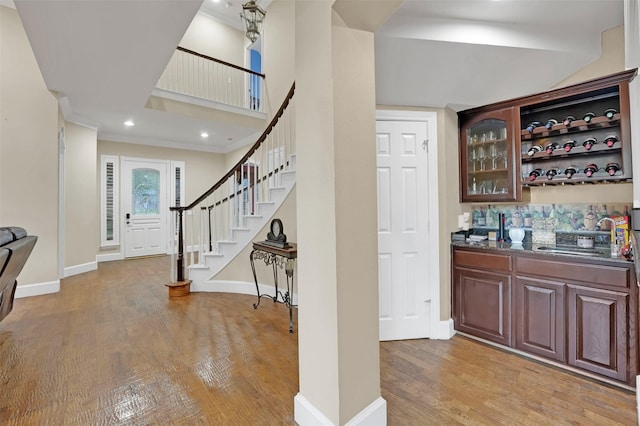 bar with sink, light wood-type flooring, and tasteful backsplash