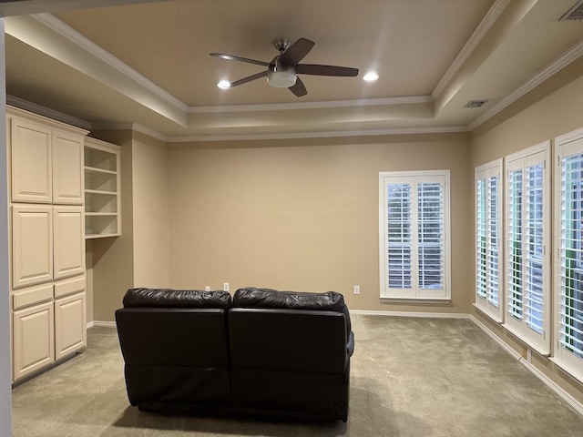 carpeted living room with ornamental molding, ceiling fan, and a raised ceiling