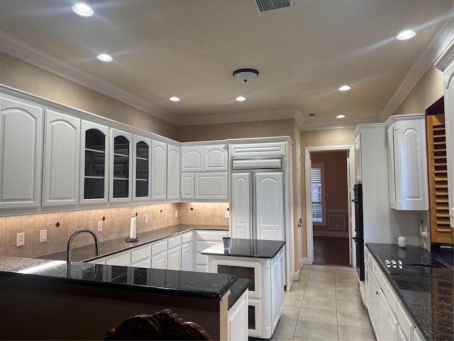 kitchen featuring white cabinetry, light tile patterned flooring, a center island, dark stone countertops, and black appliances