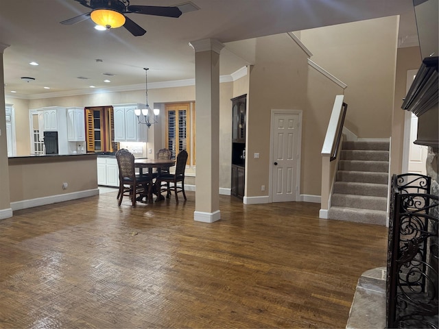 dining room featuring crown molding, dark wood-type flooring, ceiling fan with notable chandelier, and decorative columns