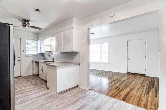 kitchen featuring white cabinets, decorative backsplash, light stone countertops, and sink