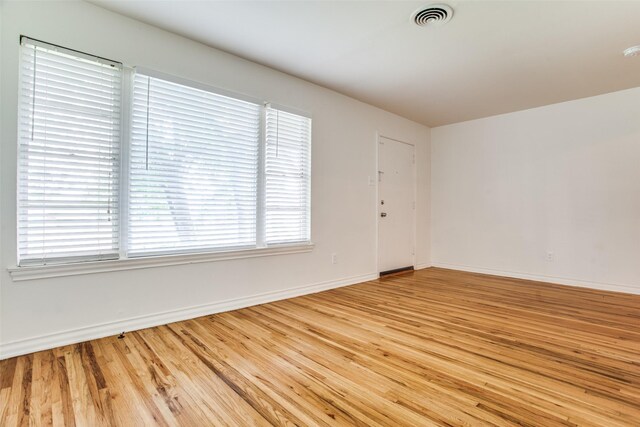 empty room with a notable chandelier and light wood-type flooring