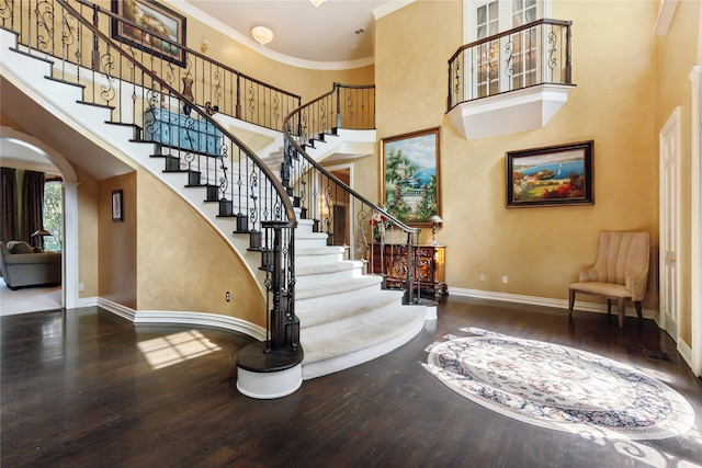 foyer entrance with hardwood / wood-style floors, a high ceiling, and ornamental molding