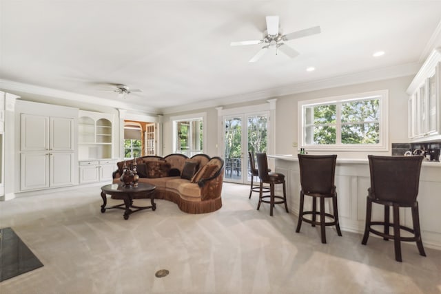 living room featuring light colored carpet, ceiling fan, and crown molding