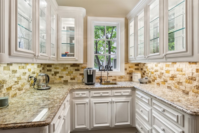 kitchen featuring white cabinetry, sink, backsplash, and light stone counters