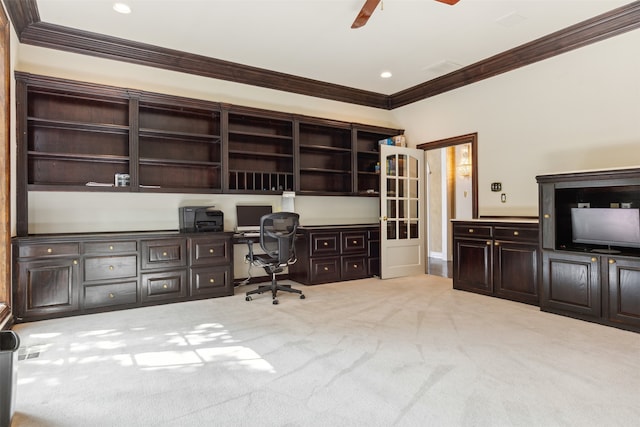 office area featuring light carpet, built in desk, ceiling fan, and crown molding