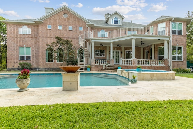 rear view of house with ceiling fan, a patio, and a swimming pool with hot tub