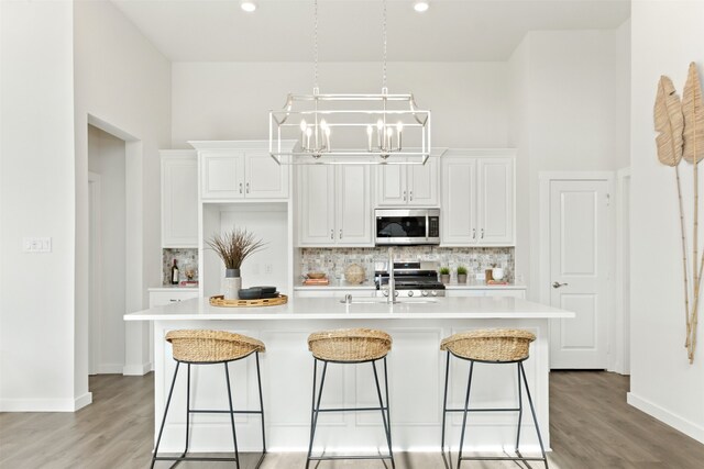 kitchen featuring sink, a kitchen island with sink, a kitchen breakfast bar, white cabinetry, and appliances with stainless steel finishes