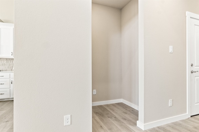 hallway featuring light wood-style flooring and baseboards