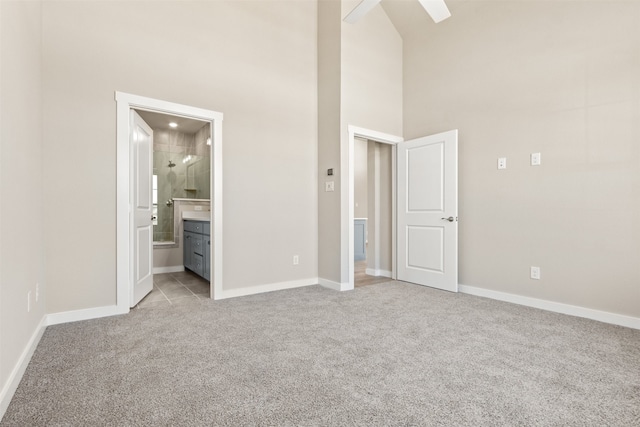 unfurnished bedroom with light carpet, a high ceiling, and baseboards