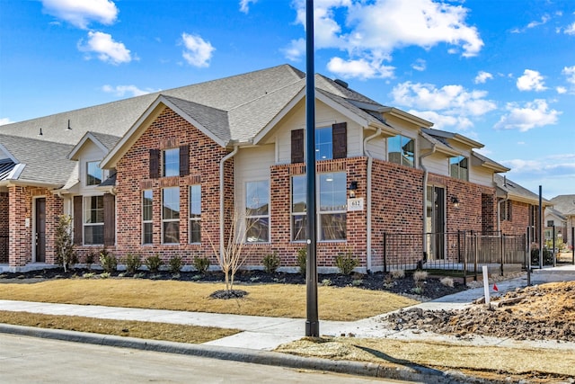 view of front of property with a front yard, brick siding, and roof with shingles