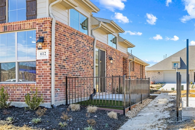 view of property exterior with fence and brick siding