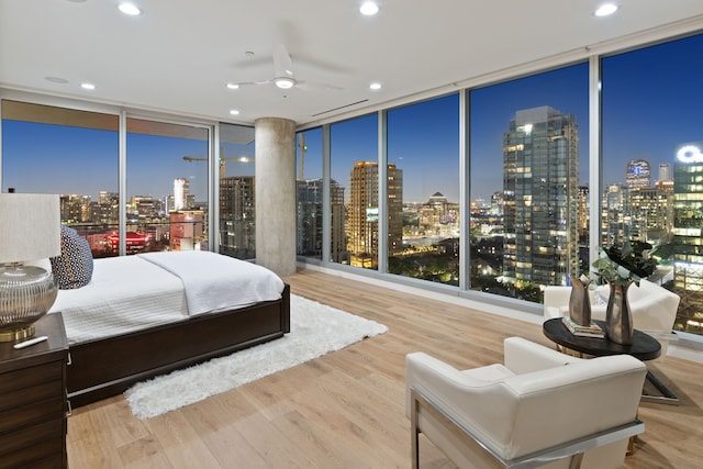 bedroom with hardwood / wood-style floors, ceiling fan, and expansive windows