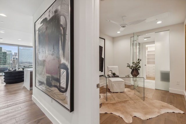 corridor with floor to ceiling windows and light hardwood / wood-style floors