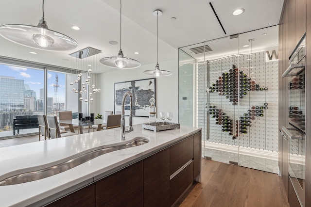 kitchen featuring decorative light fixtures, dark hardwood / wood-style flooring, dark brown cabinets, and expansive windows