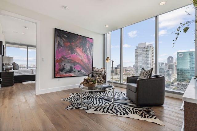 sitting room featuring a healthy amount of sunlight, a wall of windows, and hardwood / wood-style flooring