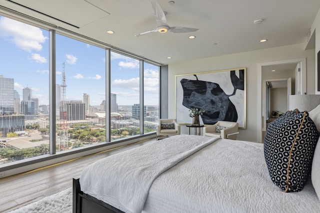 bedroom featuring ceiling fan, hardwood / wood-style flooring, multiple windows, and floor to ceiling windows