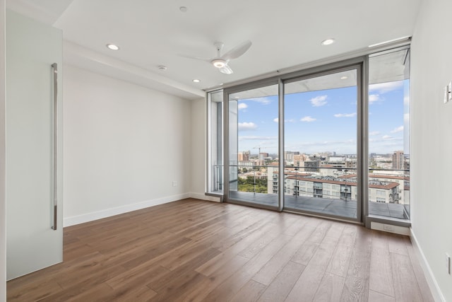 unfurnished room with floor to ceiling windows, hardwood / wood-style flooring, and ceiling fan