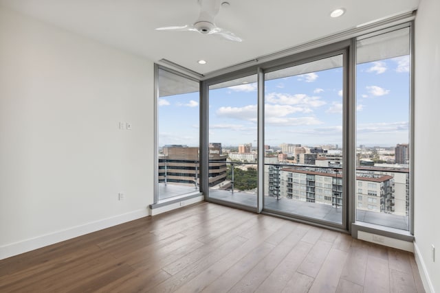 empty room with wood-type flooring, ceiling fan, and expansive windows