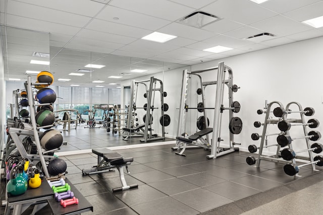 workout area featuring a paneled ceiling and expansive windows