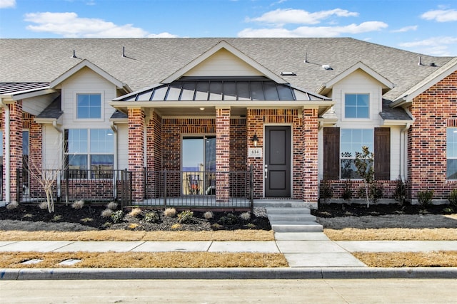 view of front facade featuring metal roof, covered porch, brick siding, roof with shingles, and a standing seam roof