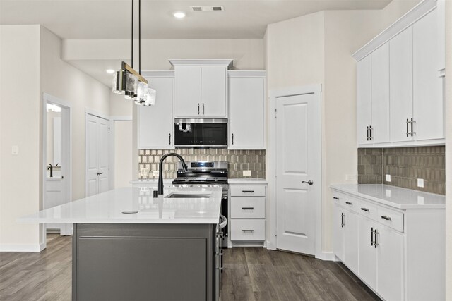 kitchen with hanging light fixtures, a kitchen island with sink, white cabinetry, light wood-type flooring, and appliances with stainless steel finishes