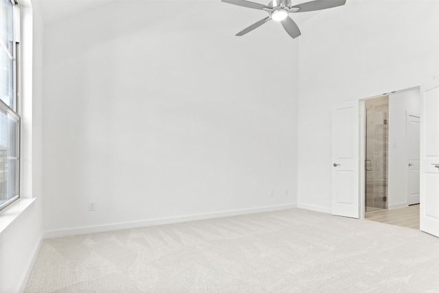 carpeted spare room with ceiling fan and a high ceiling