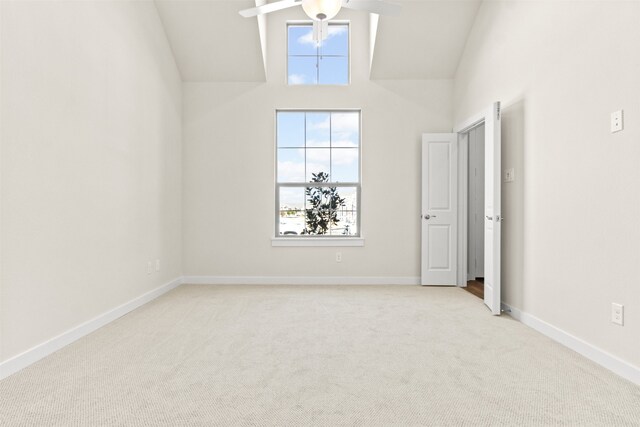 spare room with high vaulted ceiling, light colored carpet, and ceiling fan