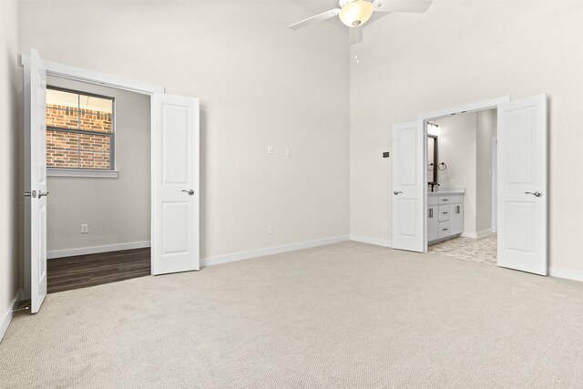 unfurnished bedroom featuring ceiling fan, connected bathroom, and light carpet