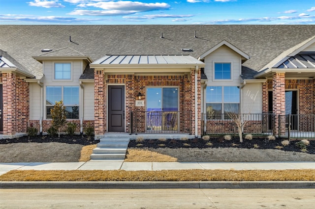 view of front of home featuring a standing seam roof, a shingled roof, metal roof, and brick siding