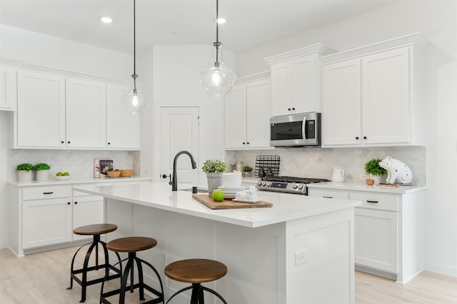 kitchen with a center island with sink, decorative backsplash, and appliances with stainless steel finishes