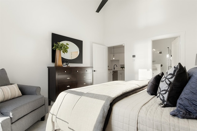 bedroom featuring connected bathroom, ceiling fan, sink, and a high ceiling