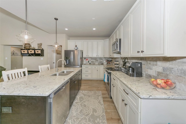 kitchen with white cabinetry, sink, light hardwood / wood-style floors, a center island with sink, and appliances with stainless steel finishes