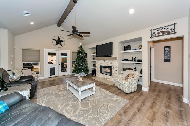 living room featuring hardwood / wood-style flooring, beam ceiling, built in features, and a fireplace