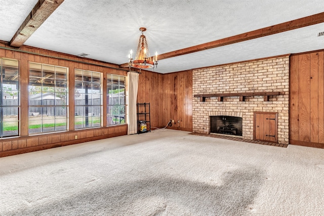 unfurnished living room featuring a wealth of natural light, wood walls, and a textured ceiling