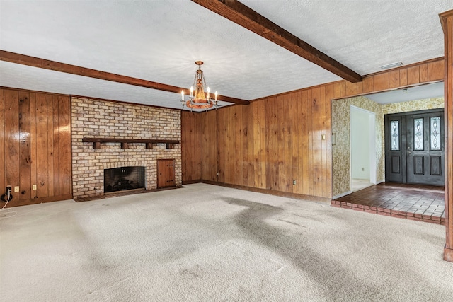 unfurnished living room with beamed ceiling, wooden walls, carpet, and a brick fireplace