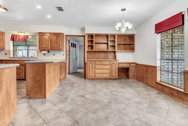 kitchen featuring pendant lighting, sink, backsplash, and an inviting chandelier