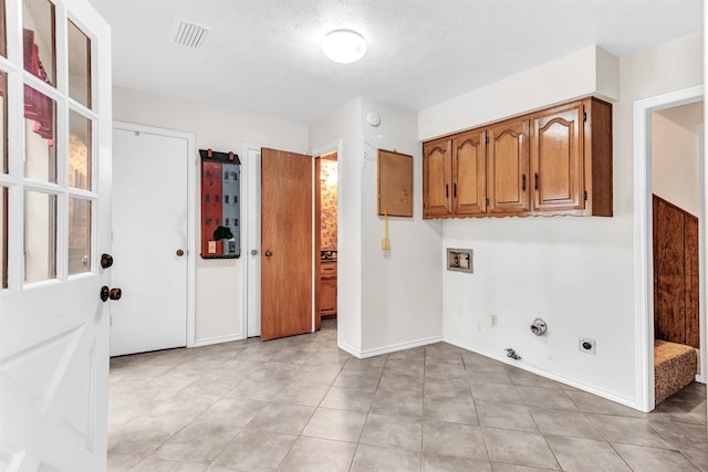 clothes washing area with light tile patterned flooring, a textured ceiling, hookup for an electric dryer, hookup for a washing machine, and hookup for a gas dryer