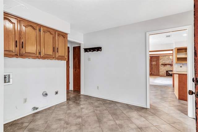 laundry area featuring electric dryer hookup, cabinets, gas dryer hookup, light tile patterned floors, and washer hookup