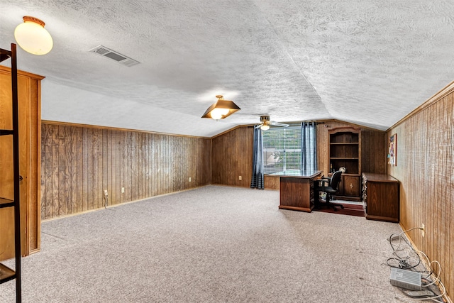 unfurnished office featuring wood walls, a textured ceiling, and carpet floors