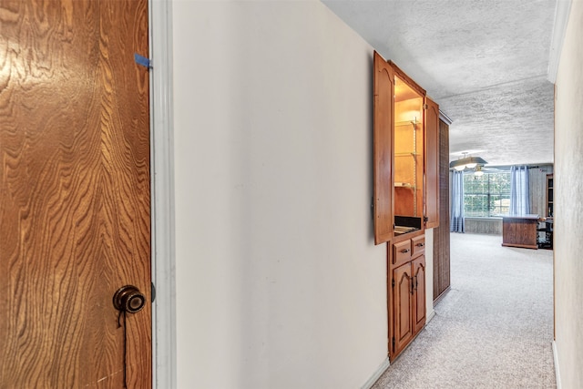 hall featuring a textured ceiling and light carpet