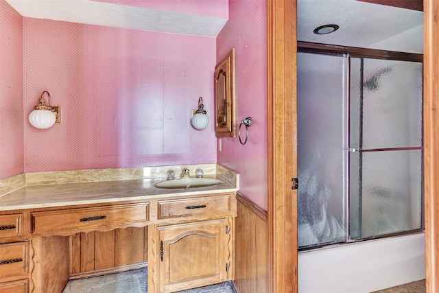 bathroom featuring vanity, a textured ceiling, and shower / bath combination with glass door