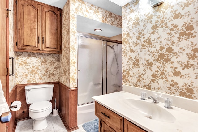 full bathroom featuring toilet, tile patterned flooring, a textured ceiling, combined bath / shower with glass door, and vanity