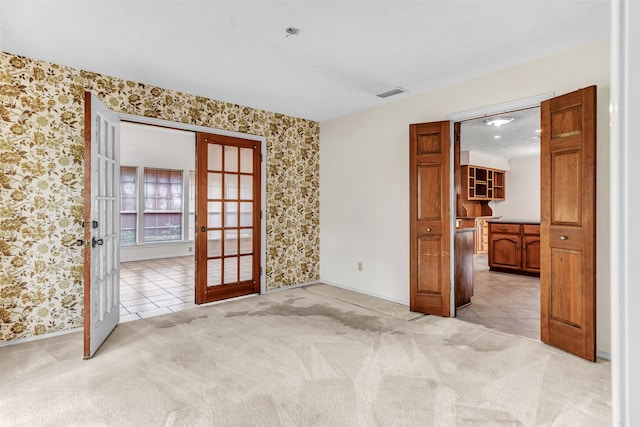 carpeted spare room featuring french doors