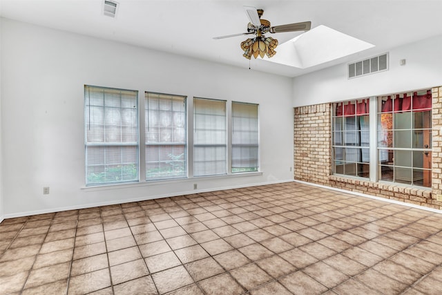 spare room featuring tile patterned floors, ceiling fan, and a skylight