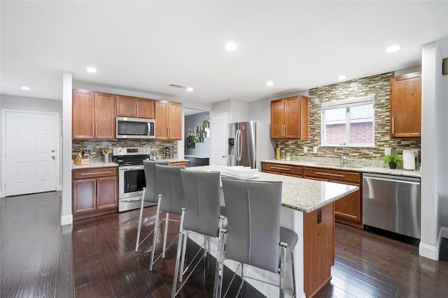 kitchen with a center island, stainless steel appliances, dark hardwood / wood-style floors, and a breakfast bar area