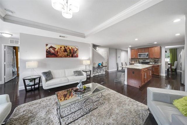 living room featuring a stone fireplace, dark hardwood / wood-style flooring, ornamental molding, and a tray ceiling