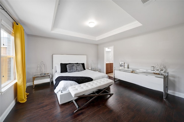 bedroom with dark hardwood / wood-style floors, connected bathroom, and a tray ceiling